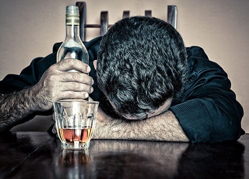 Man with bottle passed out on table needs to know can you die from alcohol withdrawal