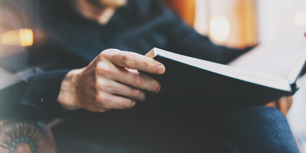 man sitting in chair doing drug rehab reading