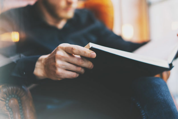 man sitting in chair doing drug rehab reading