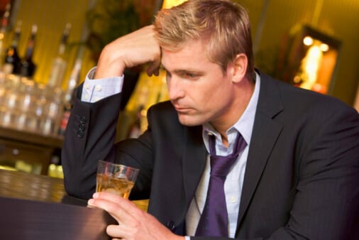 Distraught Executive man holding a drink at a bar needing an executive drug detox program