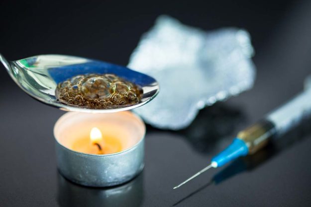 spoon of heroin over a candle next to a syringe displaying the need for heroin treatment facilities in FL