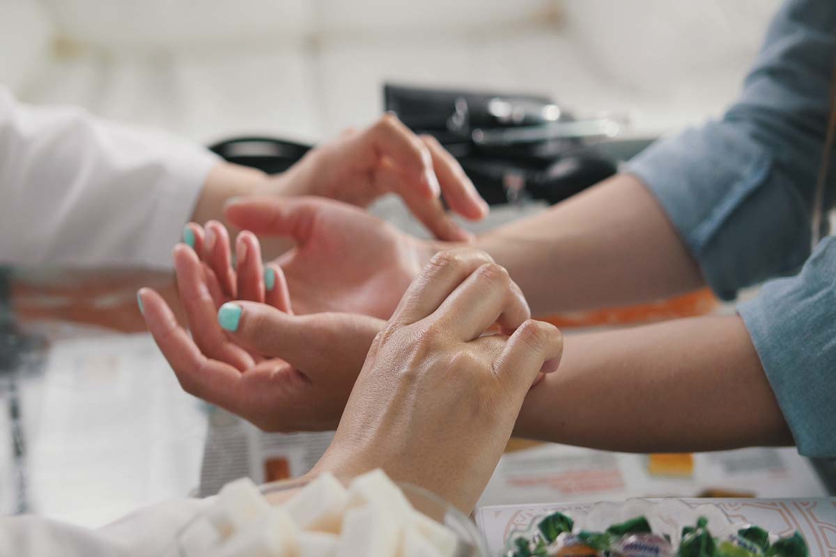 holistic rehab specialist touching wrists of addiction treatment patient