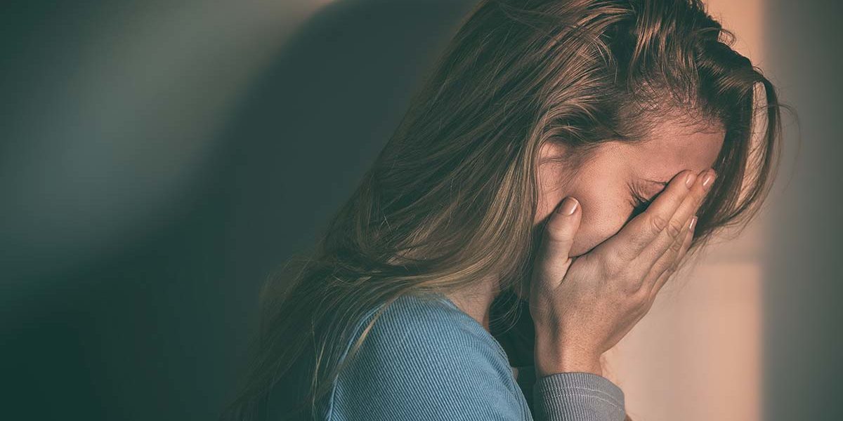 young woman covering her face from the disease of addiction