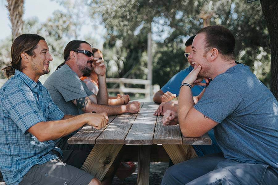 Six patients sitting at a picnic table laughing
