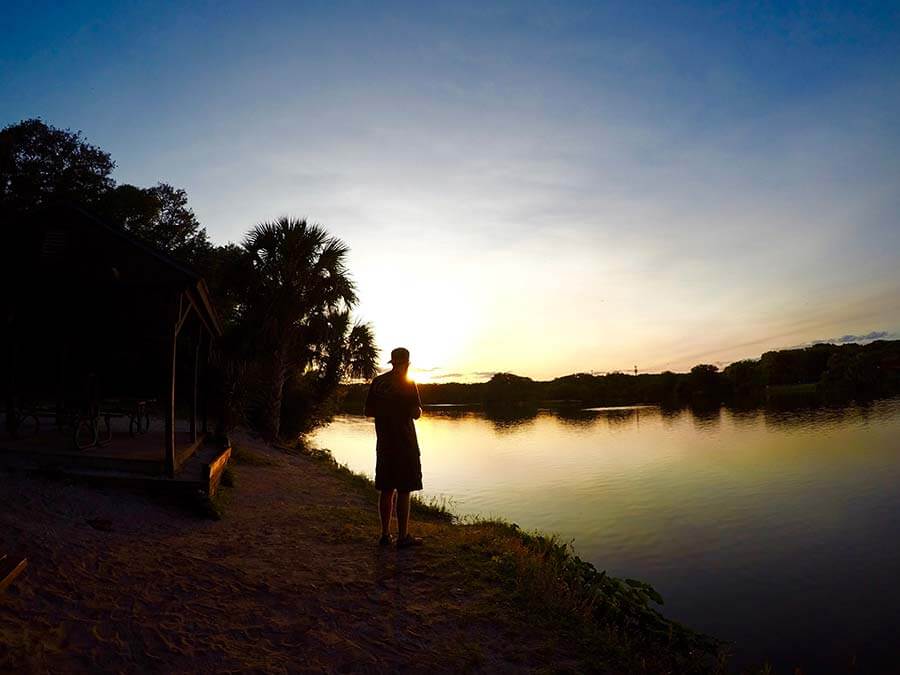 Man standing by a lake at sunset