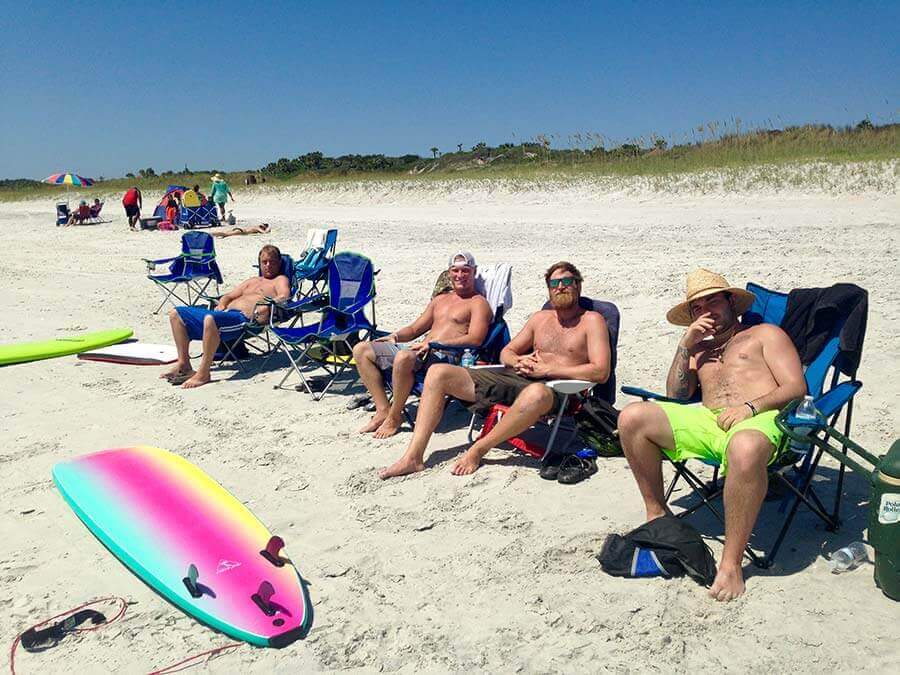 Four men sitting in chairs on the beach