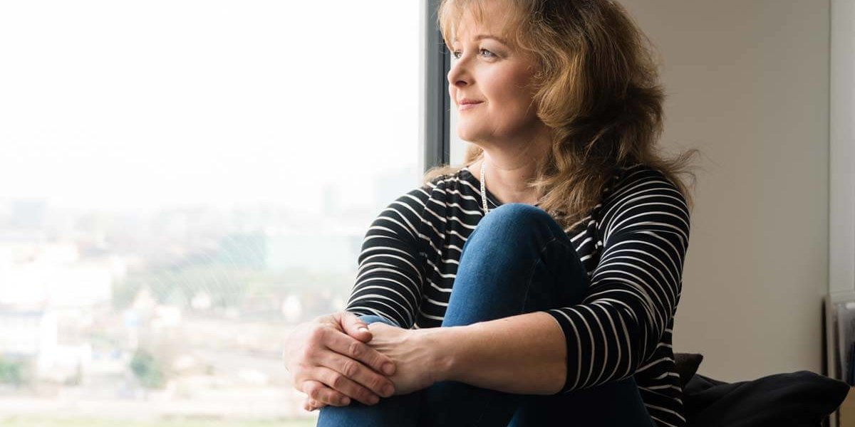 woman looking out the window of a drug and alcohol rehabilitation center