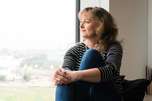 woman looking out the window of a drug and alcohol rehabilitation center