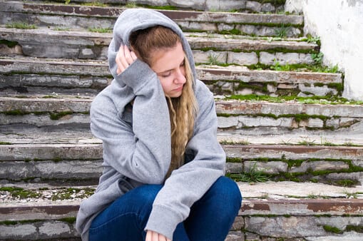 Young woman on steps feeling effects of drug withdrawal.