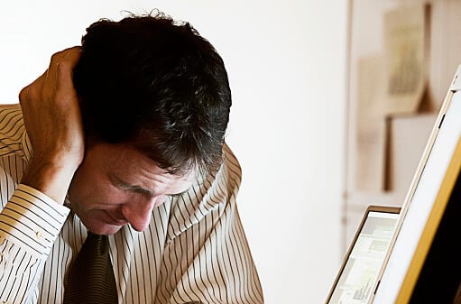 Man holding head is hoping his signs of an alcoholic are not noticeable.