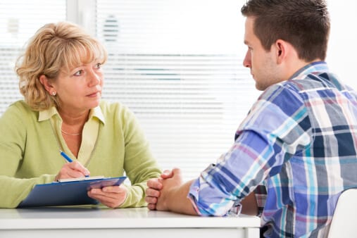 Female therapist conducting psychotherapy session with young man.