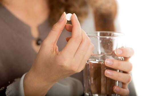 Female hand holding a pill which may signal her drug dependence.