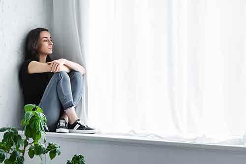 person sitting on window sill thinking about mental health and substance abuse