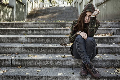 Young girl on steps in hoodie frustrated on what to do about cocaine addiction treatment she knows she needs.