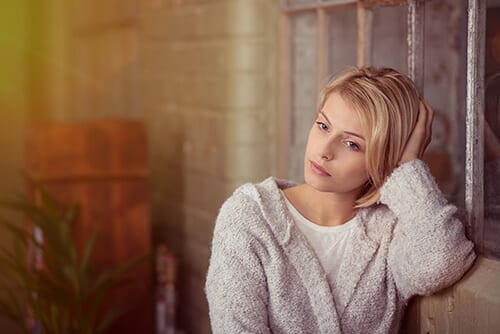 Woman leaning on wall after learning about her alcohol detox timeline for recovery.