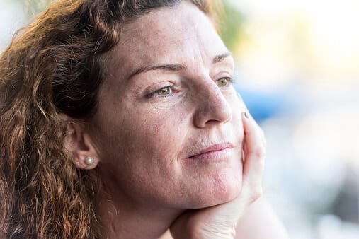 Woman with hand on chin contemplating getting help after hearing drug overdose statistics.