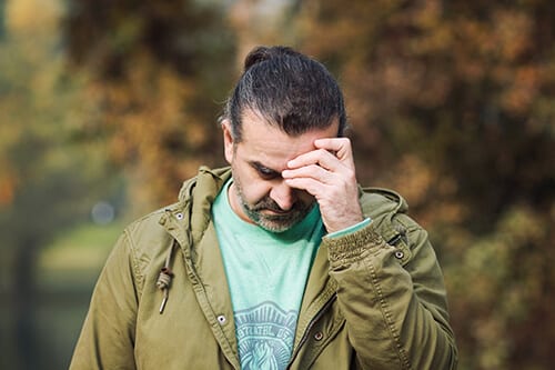 Guy outside with hand to head knows extended care in rehab will extend his sobriety.