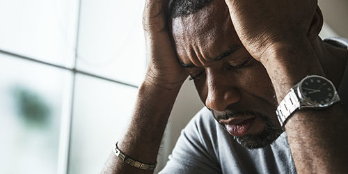 individual holding head in hands because of addiction