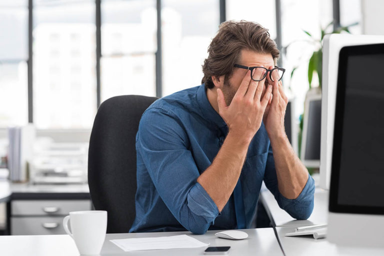man rubbing face needing stress management techniques at work