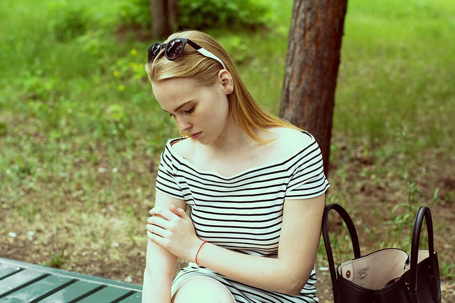 Woman on bench looking down, ready for medical detox at Beaches.