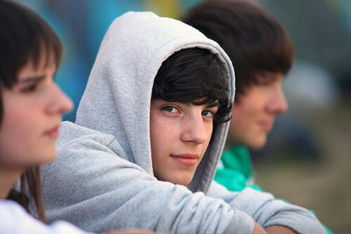 Boy in hoodie smirking about teen substance abuse.