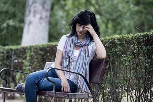 Woman on a park bench is contemplating how to deal with drug withdrawal symptoms.