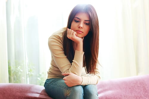 Young woman on red couch contemplating some substance abuse preventions