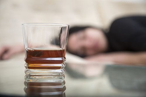 Woman laying on table in background drink in foreground already knows the alcohol use disorder definition.