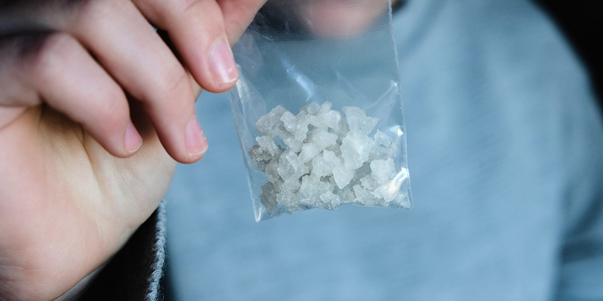 individual holding up a baggy of meth to show the effects of meth