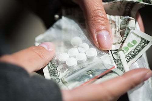 Money and pills changing hands means opioid drug abuse.