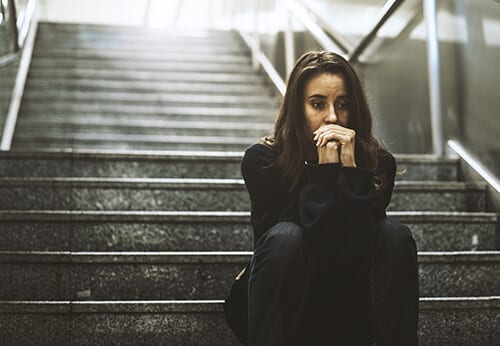 Sad woman on steps worrying about her fentanyl abuse.