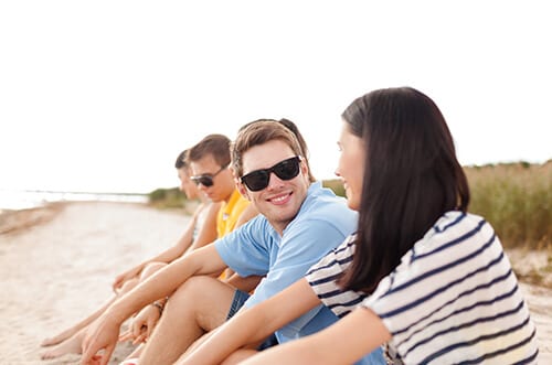 Group of young people on beach enjoying Florida sober living.