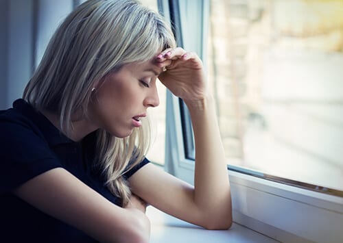 Woman at window with hand to head showing signs of Valium abuse.
