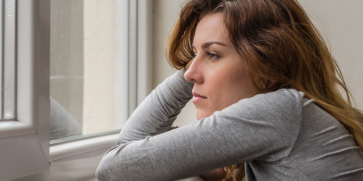 a woman stares out the window as she thinks about depression and addiction