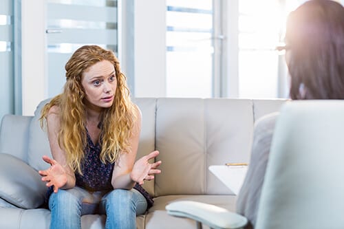 Aggravated young woman talking to counselor about her codependency recovery.