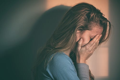 Distressed woman hiding face wants to know how to fight addiction.