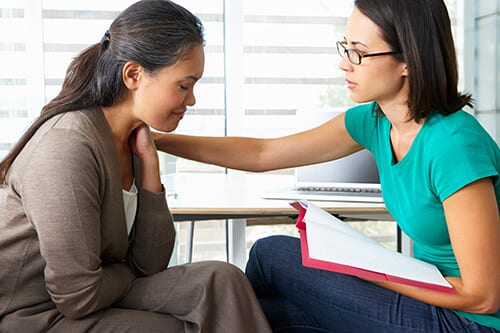 Two woman discussing, one comforting another, about the signs of codependency.