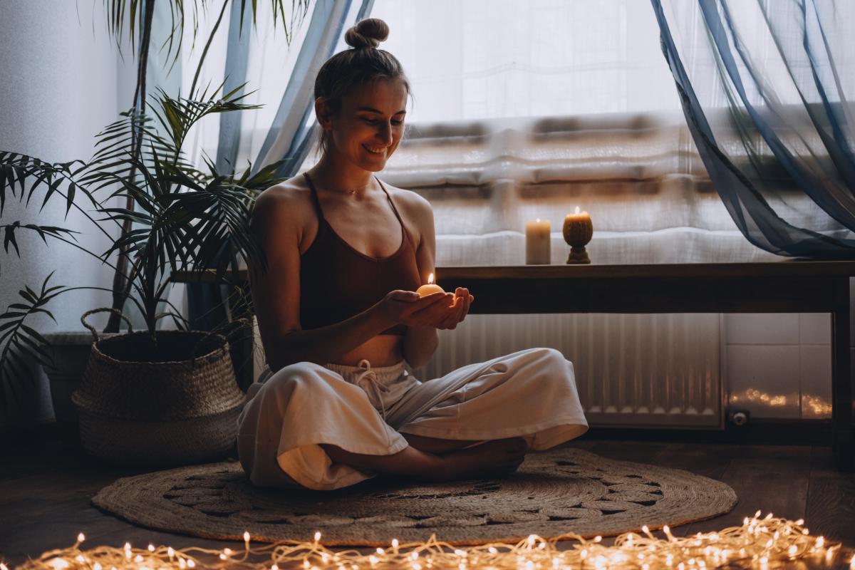 woman meditating surrounded by lights and candles