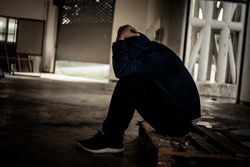 Person in dark alley suffering heroin use symptoms.