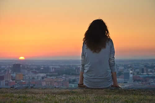 Young person sitting on a wall wishing she had been successful in preventing addiction