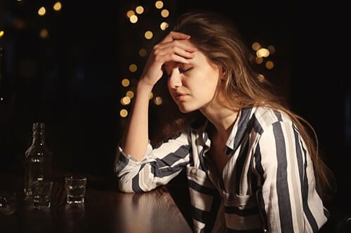 Woman at bar seeming hopeless wants to avoid her chronic alcohol abuse