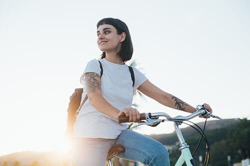 Woman in sun riding a bike as part of experiential therapy activities during addiction treatment