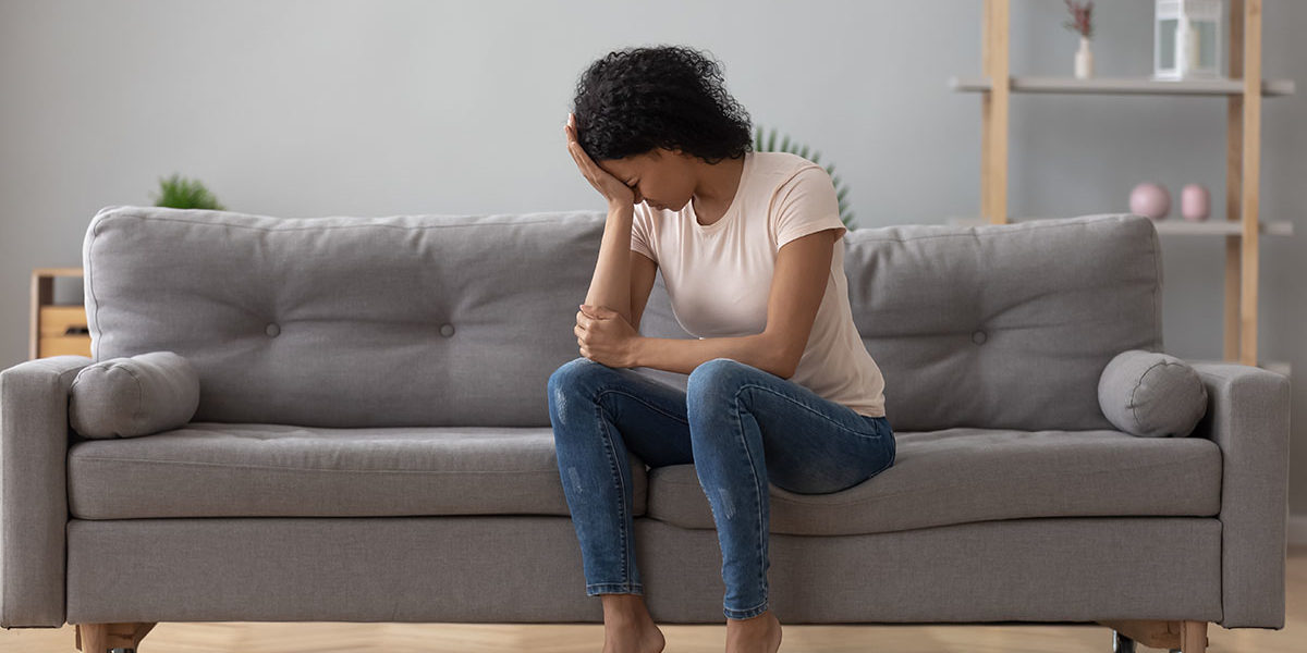 woman on couch with head in her hand from Side Effects of Xanax abuse