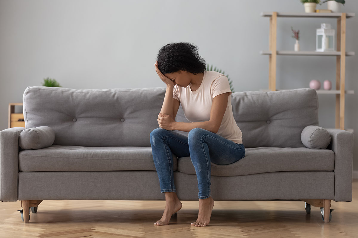 woman on couch with head in her hand from Side Effects of Xanax abuse