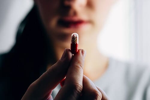 Woman holding a pill which could be the precursor to a stimulant detox program