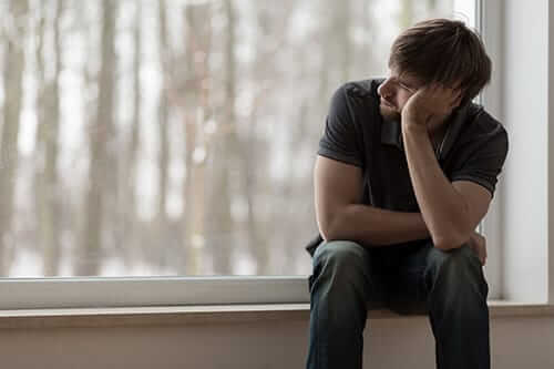 Sad man at window during an alcohol withdrawal treatment program