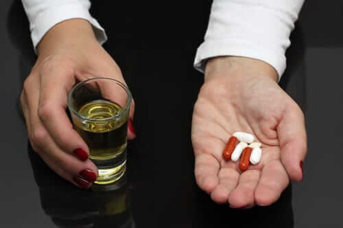 Hands with pills and alcohol show a need for drug and alcohol evaluation for addiction treatment
