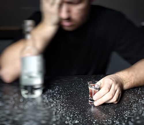Man in front of shot glass wonders how he got to alcohol relapse
