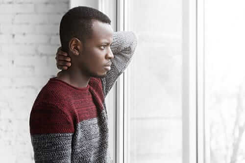 Man looking out window of prescription opioid rehab for men