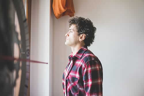 Male college student staring out window after taking study drugs for finals.